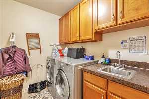 Laundry room with cabinets, sink, washing machine and dryer, and tile flooring on main floor
