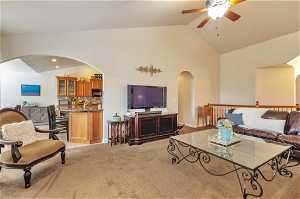 Living room with high vaulted ceiling, light colored carpet, and ceiling fan