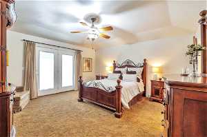 Bedroom with light carpet, access to outside, a tray ceiling, and ceiling fan