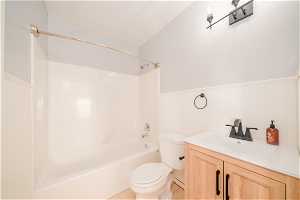 Full bathroom with toilet, vaulted ceiling, tile flooring, vanity, and bathtub / shower combination