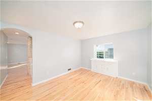 Empty room with brick wall and light hardwood / wood-style floors