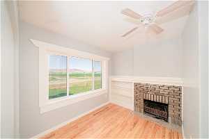 Unfurnished living room featuring light hardwood / wood-style floors, a fireplace, and ceiling fan