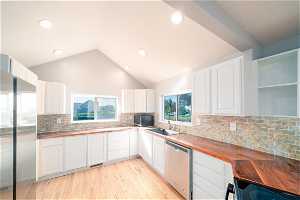 Kitchen with white cabinetry, light hardwood / wood-style floors, wood counters, dishwasher, and tasteful backsplash