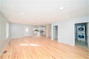 Unfurnished living room with stacked washer and clothes dryer and light hardwood / wood-style floors