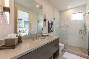 Bathroom with a shower with door, tile floors, vanity with extensive cabinet space, and toilet
