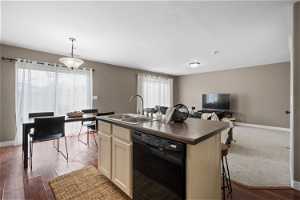 Kitchen with black dishwasher, decorative light fixtures, sink, and a wealth of natural light