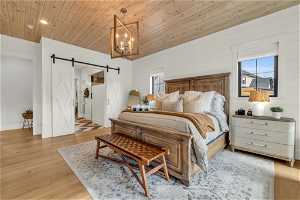 Bedroom with a barn door, wood ceiling, an inviting chandelier, and light wood-type flooring