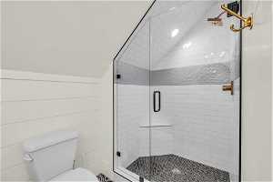 Bathroom with lofted ceiling, toilet, and walk in shower