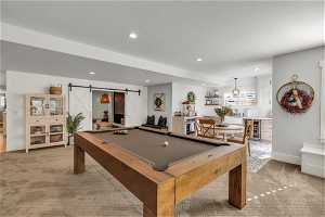 Game room featuring billiards, a barn door, light colored carpet, and beverage cooler
