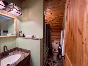 Full bathroom featuring vanity, toilet, combined bath / shower with glass door, and tile floors