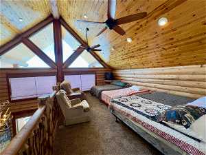 Carpeted bedroom featuring high vaulted ceiling, beam ceiling, wooden ceiling, rustic walls, and ceiling fan