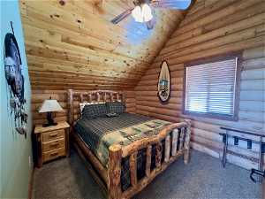 Carpeted bedroom with ceiling fan, log walls, vaulted ceiling, and wood ceiling