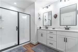 Bathroom with a shower with door, double vanity, and hardwood / wood-style flooring