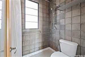 Bathroom with a shower with curtain, toilet, and tile walls