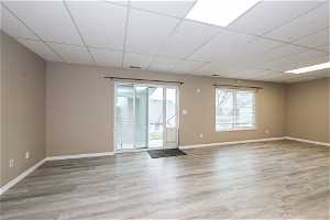 Unfurnished room with a paneled ceiling, plenty of natural light, and light hardwood / wood-style floors