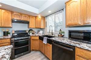 Kitchen featuring light stone countertops, light hardwood / wood-style floors, sink, and stainless steel appliances