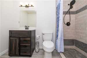 Bathroom featuring toilet, tiled shower, large vanity, and hardwood / wood-style flooring