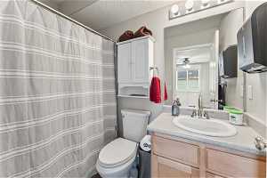 Mainfloor Bathroom with a textured ceiling, oversized vanity, ceiling fan, and toilet