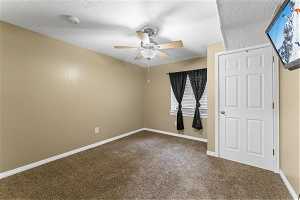Bedroom 4 with dark colored carpet, ceiling fan, and a textured ceiling