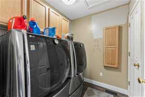 Laundry area with a textured ceiling, separate washer and dryer, cabinets, and dark hardwood / wood-style flooring