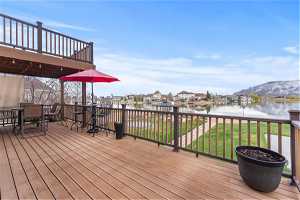 Wooden Deck and partial covered section with a water and mountain view and a lawn