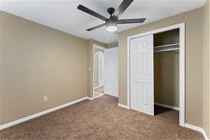 Bedroom 5 featuring a closet, ceiling fan, and dark colored carpet