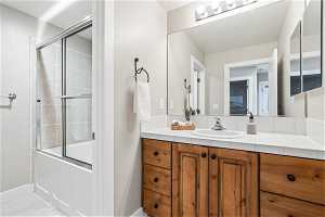 Bathroom featuring shower / bath combination with glass door, vanity, and tile flooring