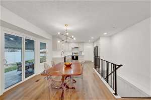 Dining space featuring light hardwood floors, chandelier, and new rod iron railing