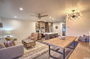 Living room with sink, ceiling fan with notable chandelier, and dark hardwood / wood-style flooring