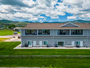 Back of house featuring a lawn, a patio area, and a mountain view