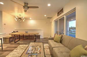 Living room featuring dark hardwood / wood-style floors and ceiling fan with notable chandelier