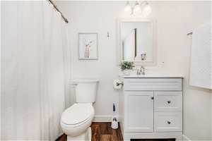 Bathroom with toilet, large vanity, and hardwood / wood-style flooring