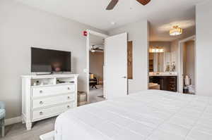 Carpeted primary bedroom with ensuite bathroom and ceiling fan