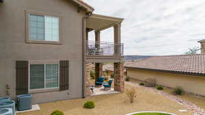 Back of property featuring a balcony, a patio area, a pergola, and central AC