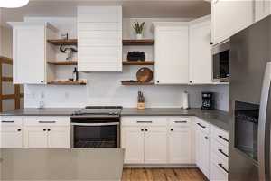 Kitchen with appliances with stainless steel finishes, white cabinetry, and light wood-type flooring