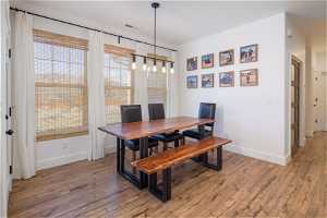 Dining space with light hardwood / wood-style floors and a notable chandelier