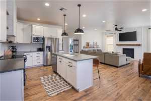 Kitchen with white cabinetry, ceiling fan, appliances with stainless steel finishes, sink, and light wood-type flooring