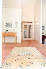 Entryway with light tile floors, high vaulted ceiling, and french doors