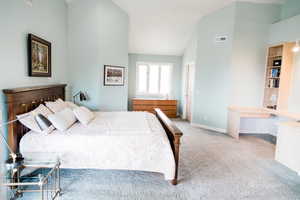 Master bedroom with high vaulted ceiling and light colored carpet