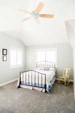 Carpeted bedroom featuring vaulted ceiling and ceiling fan