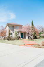 View of front of property with a front lawn, custom landscaping and stone walkway