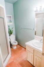 Bathroom featuring walk in shower, toilet, tile floors, and vanity