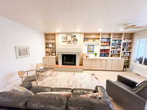 Living room with built in features, ceiling fan, and LVP flooring