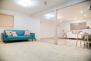 Basement Family room featuring rail lighting, beam ceiling, and LVP flooring