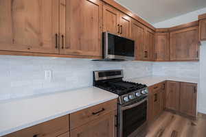 Kitchen featuring appliances with stainless steel finishes, light hardwood / wood-style floors, and decorative backsplash