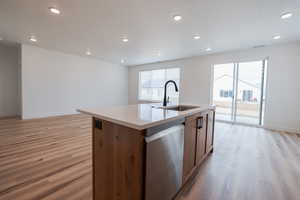 Kitchen featuring an island with sink, dishwasher, light hardwood / wood-style flooring, and sink