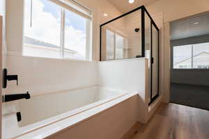 Bathroom featuring independent shower and bath, hardwood / wood-style flooring, and a healthy amount of sunlight