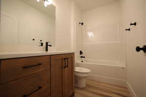 Full bathroom featuring hardwood / wood-style floors, tub / shower combination, vanity, and toilet