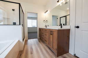 Bathroom featuring wood-type flooring, vanity, and separate shower and tub