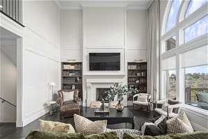 Living room featuring crown molding, built in shelves, dark wood-type flooring, and a towering ceiling